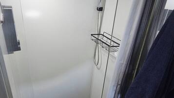 A small, enclosed shower area with a showerhead, a towel rack, and a drain.