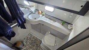 A compact bathroom with a sink, toilet, and a small window.