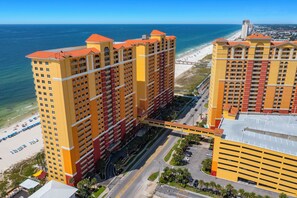 A high-rise hotel with multiple floors, a beach view, and a parking area.