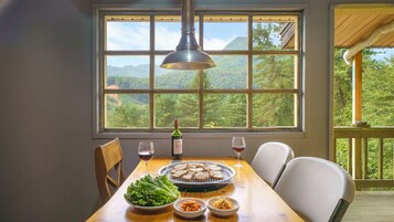 Uma mesa de jantar com uma garrafa de vinho, copos, um prato de comida e uma salada.