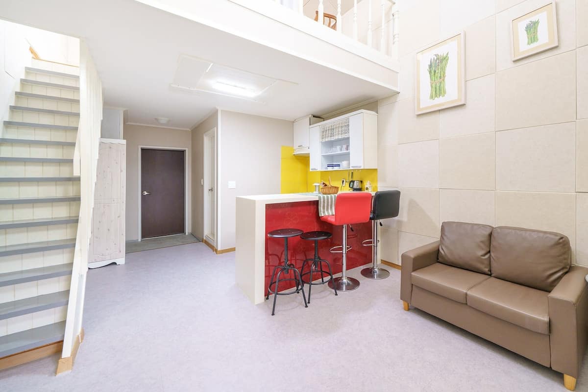 A compact living space with a kitchenette, a sofa, and a small dining table.