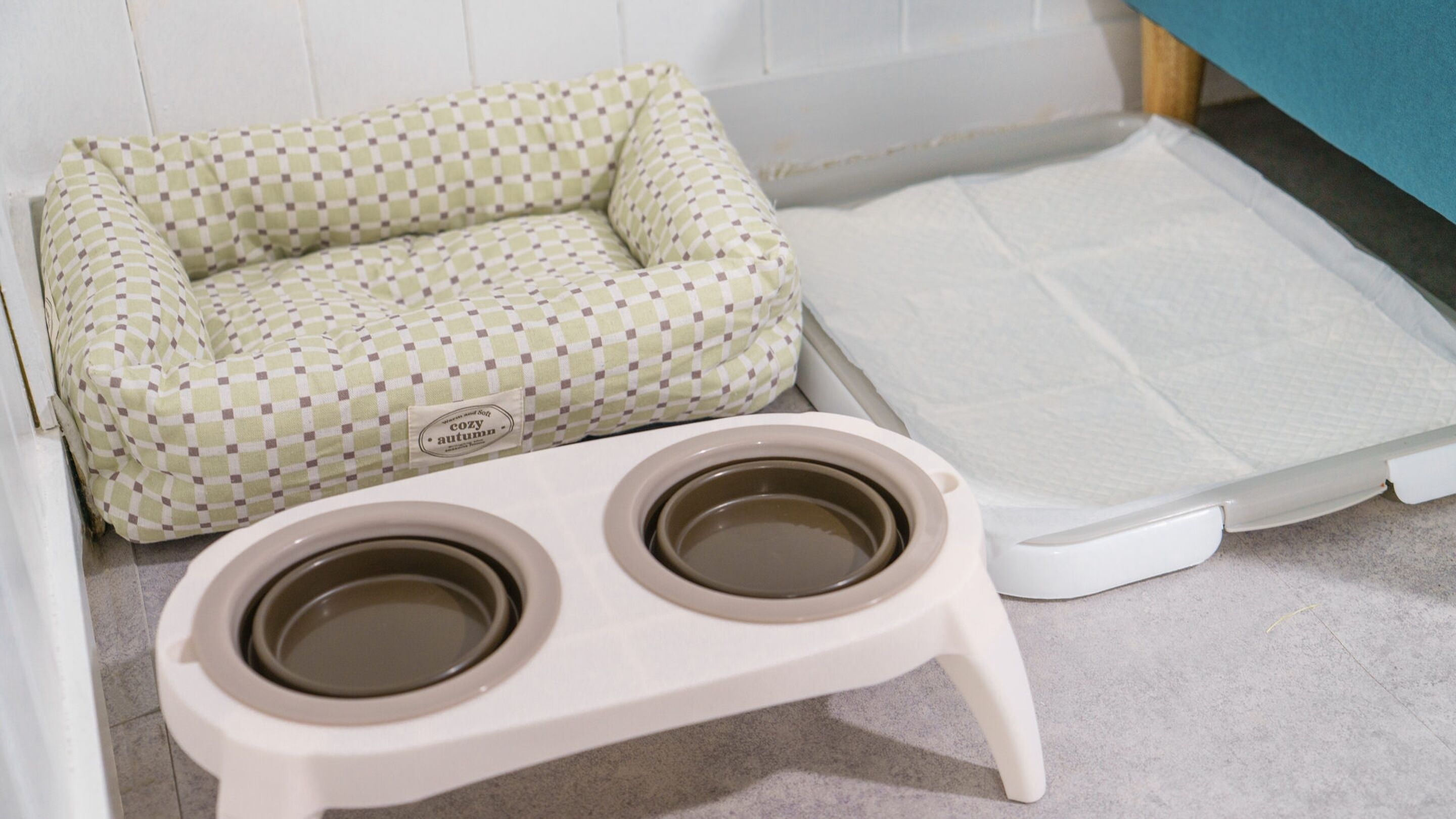 A pet bed and a pet feeding station in a room.