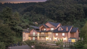 Ein mehrgeschossiges Haus mit einem Balkon, umgeben von dichtem Wald.