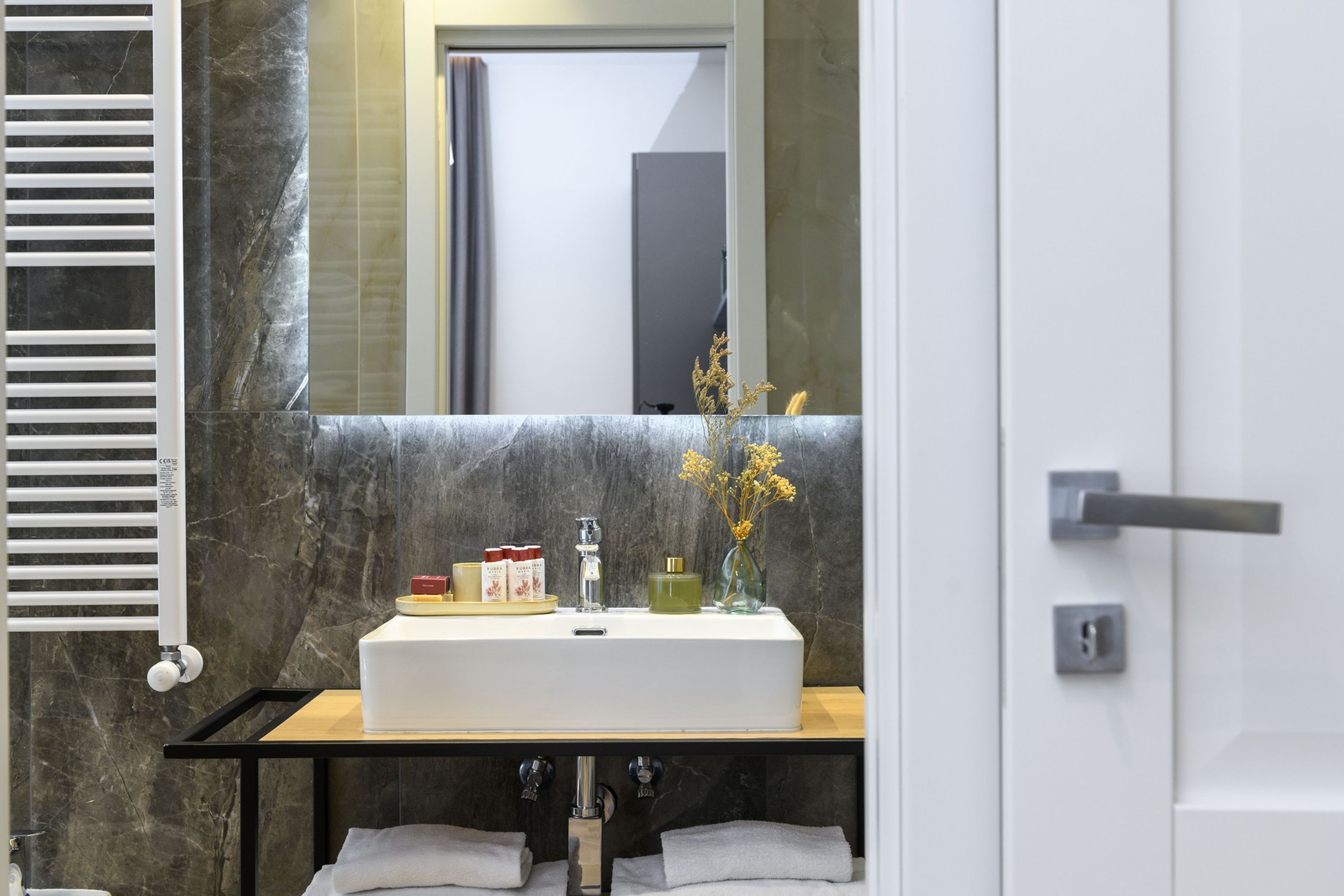 A bathroom with a white sink, a mirror, and a towel rack.