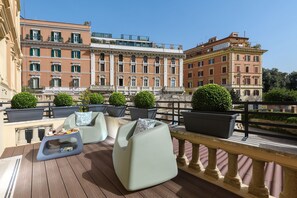 Terraza en la azotea con mobiliario exterior, plantas en macetas y vistas a edificios históricos.