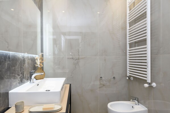 A modern bathroom with a large sink, a mirror, and a towel rack.