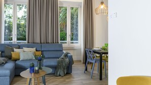A modern living room with a sofa, a small round table, and a dining area with chairs. - Domus Augustea - Nerone (Rome)