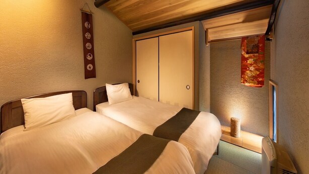 A hotel room with two beds, a wooden ceiling, a wall with a decorative panel, and a window with a curtain. - Connect inn Kyotogojo (Kyoto)