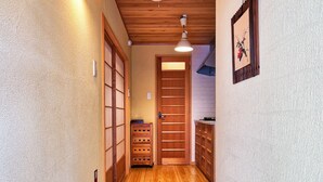 A narrow hallway with wooden flooring, a wooden door, and a small cabinet. - Connect inn Kyotogojo (Kyoto)