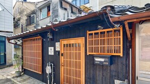 A traditional Japanese building with a dark wooden exterior, a tiled roof, and two wooden doors with vertical bars. - Connect inn Kyotogojo (Kyoto)