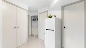 A modern kitchen with white cabinets, a white refrigerator, and a microwave.