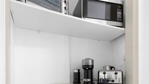 A kitchenette with a microwave, toaster, and coffee maker on the countertop.
