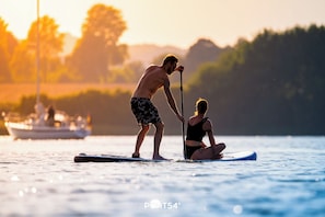 Two people on a paddleboard in a body of water with a boat in the background.