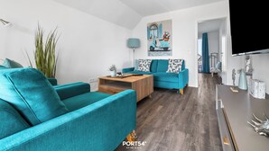 Un salon moderne avec des canapés de couleur turquoise, une table basse en bois et un tableau représentant un scooter.