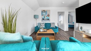 Un salon moderne avec des canapés de couleur turquoise, une table basse et un tableau représentant un scooter.