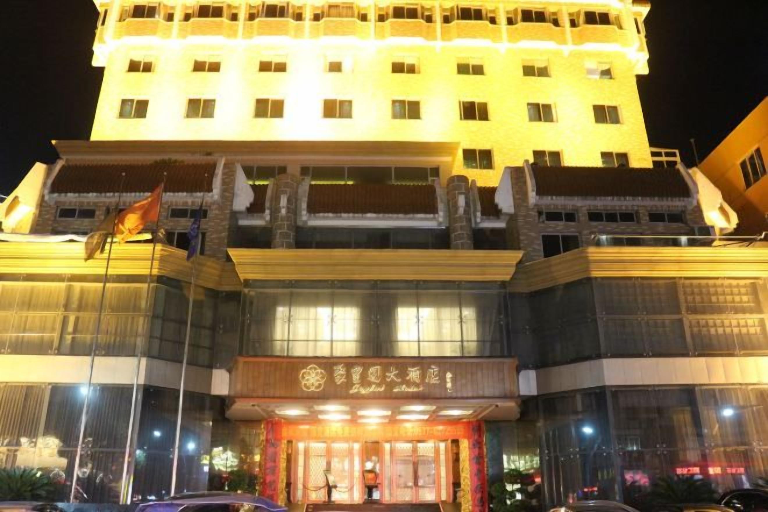 Een hotel met een opvallende ingang, grote ramen en een vlag op het dak.