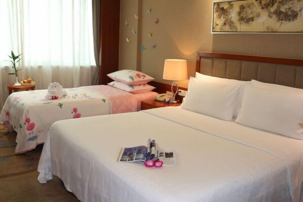 A hotel room with two beds, a nightstand, a lamp, and a wall-mounted artwork.