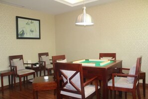 A room with a pool table, wooden chairs, a ceiling light, and a framed picture on the wall. - Joyful Hotel (Yueqing)