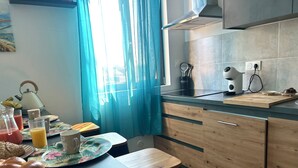 Een moderne keuken met houten kastjes, een zwart aanrecht en een raam met blauwe gordijnen.