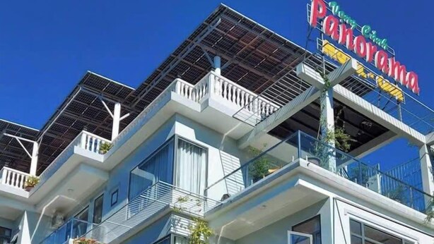 Un hôtel à plusieurs étages, reconnaissable à son enseigne bien visible où l’on peut lire « Hôtel Corona ».