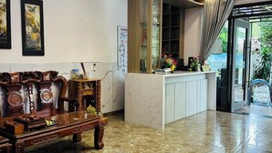 Un hall d’entrée avec un sol en marbre, un canapé en bois, un comptoir d’accueil et un lustre moderne.