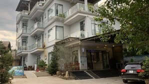 Un hôtel à plusieurs étages, doté d’un design moderne, comprenant des balcons, une entrée couverte et un espace de stationnement.
