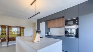 Una cocina moderna con una isla central, electrodomésticos integrados y un armario de madera sobre la encimera.