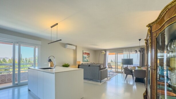 Amplia sala de estar con isla de cocina, comedor y un gran ventanal con vistas.