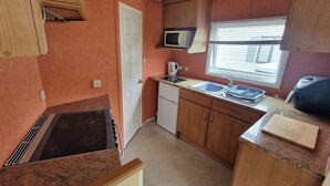 Una cucina compatta con forno a microonde, lavandino e piccolo frigorifero.