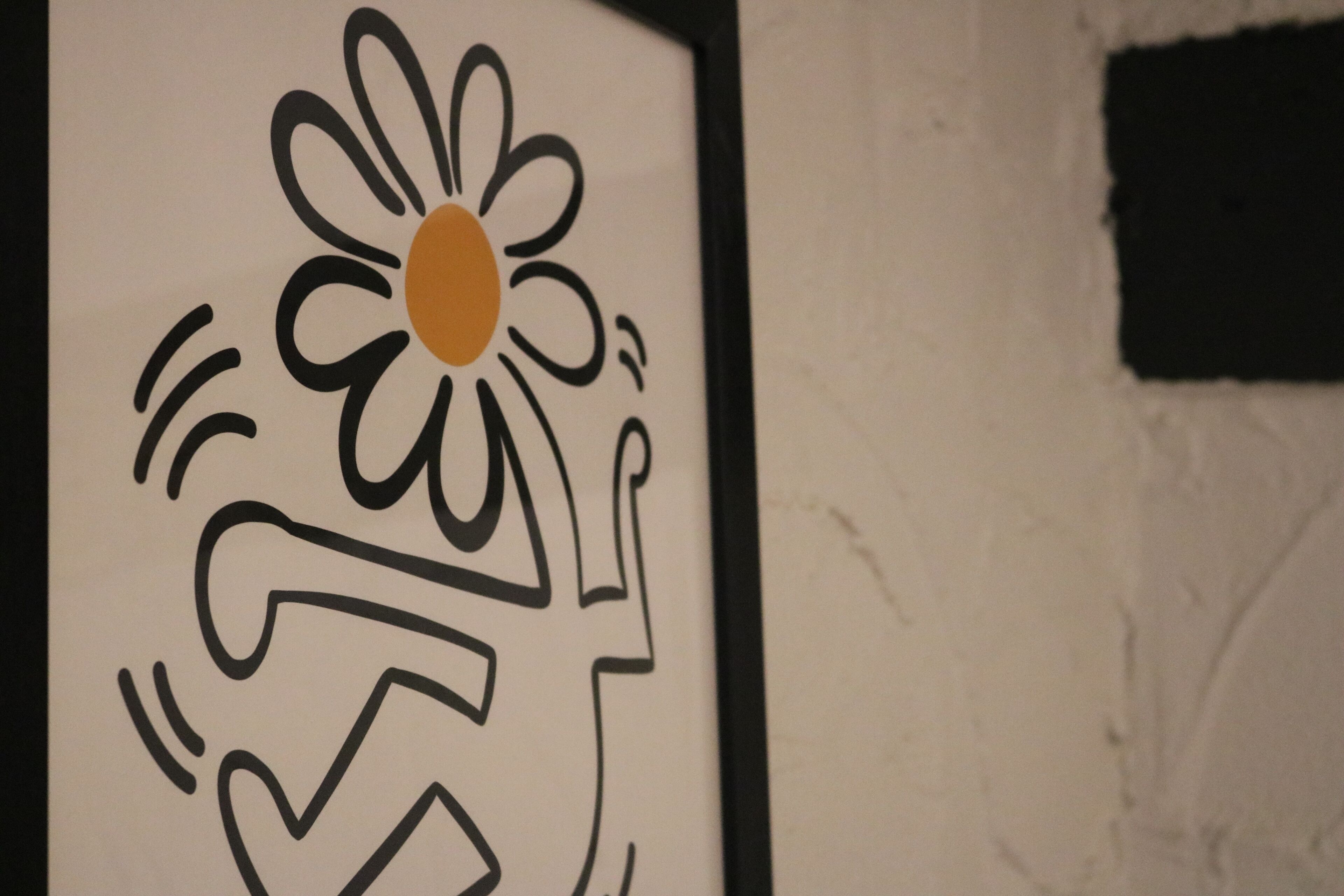 A framed artwork with a stylized flower and abstract design.