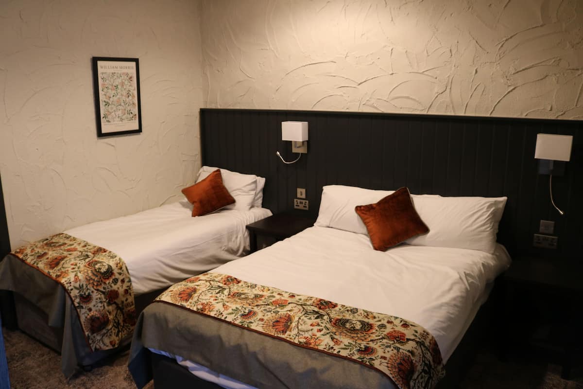 Two single beds with floral bedspreads, a framed picture on the wall, and a textured ceiling.