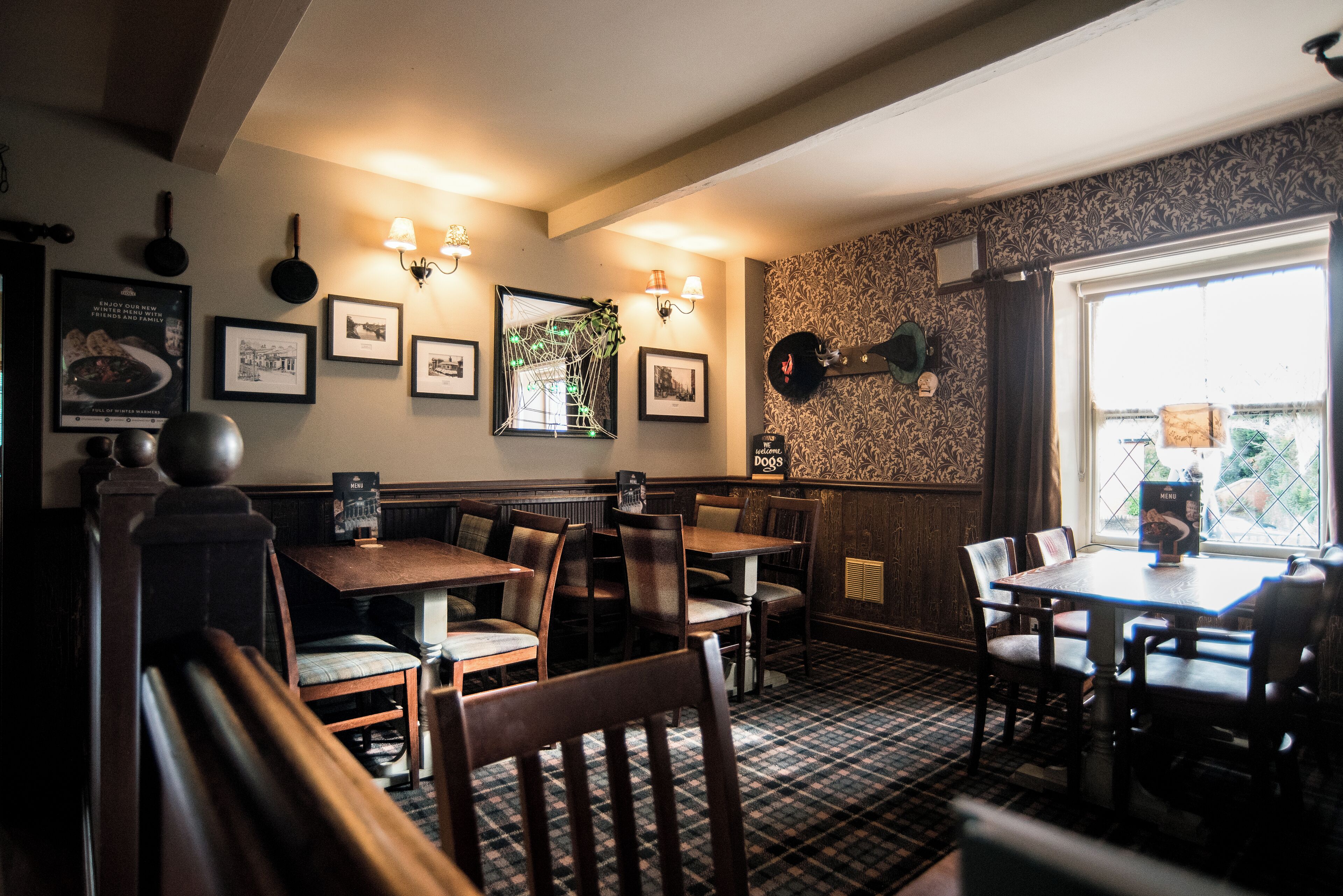 Un ristorante con tavoli e sedie in legno, quadri appesi alle pareti e un tappeto decorato.
