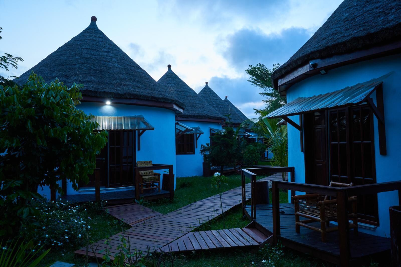 Un complexe hôtelier doté de bungalows aux toits de chaume, de passerelles en bois et d’une végétation luxuriante.