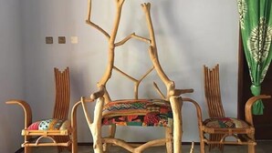 Una habitación con una silla de madera central con un cojín colorido, flanqueada por dos sillas similares con cojines estampados.