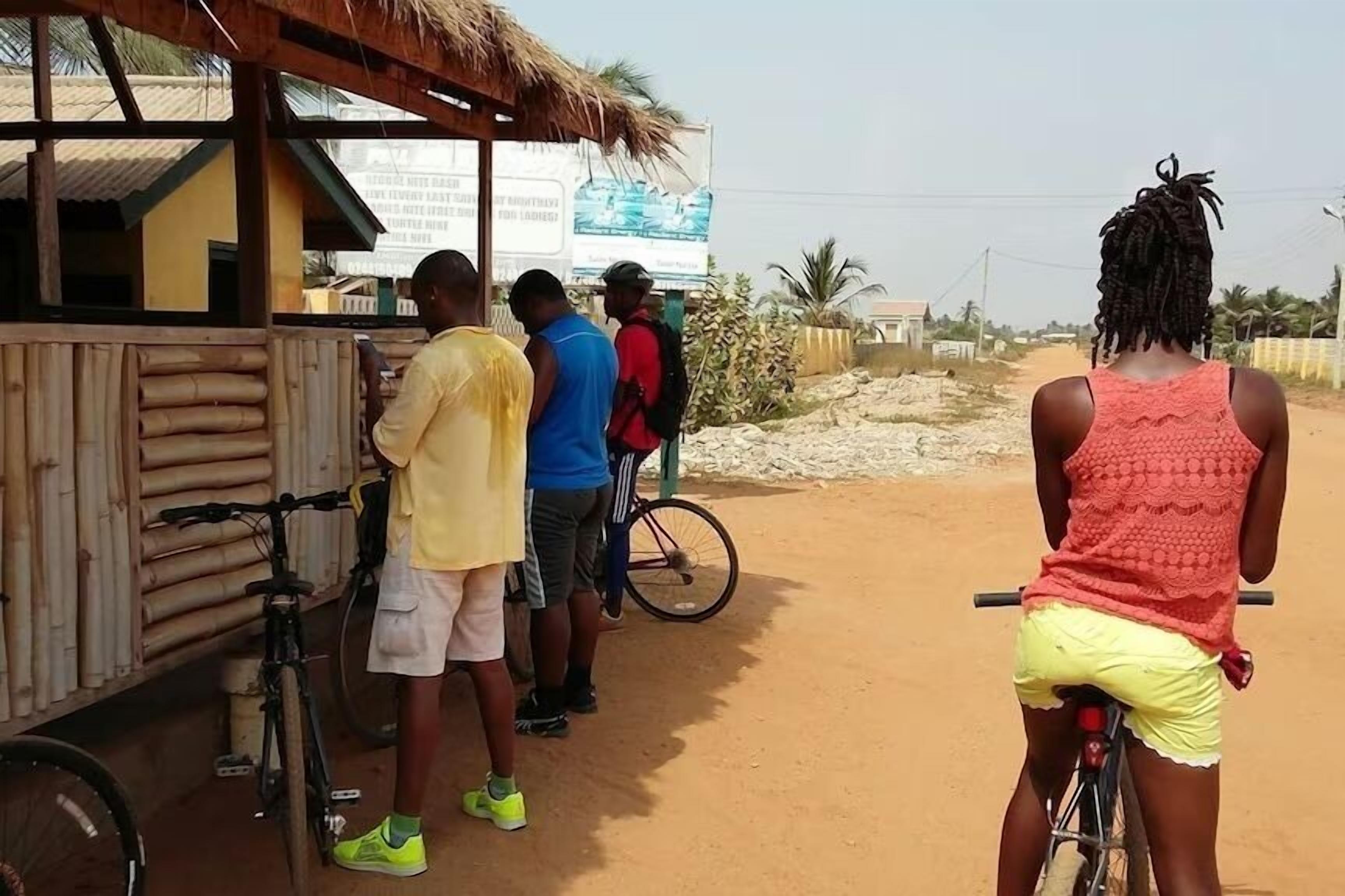 A rustic roadside stall with a thatched roof, wooden walls, and a bicycle parked in front.