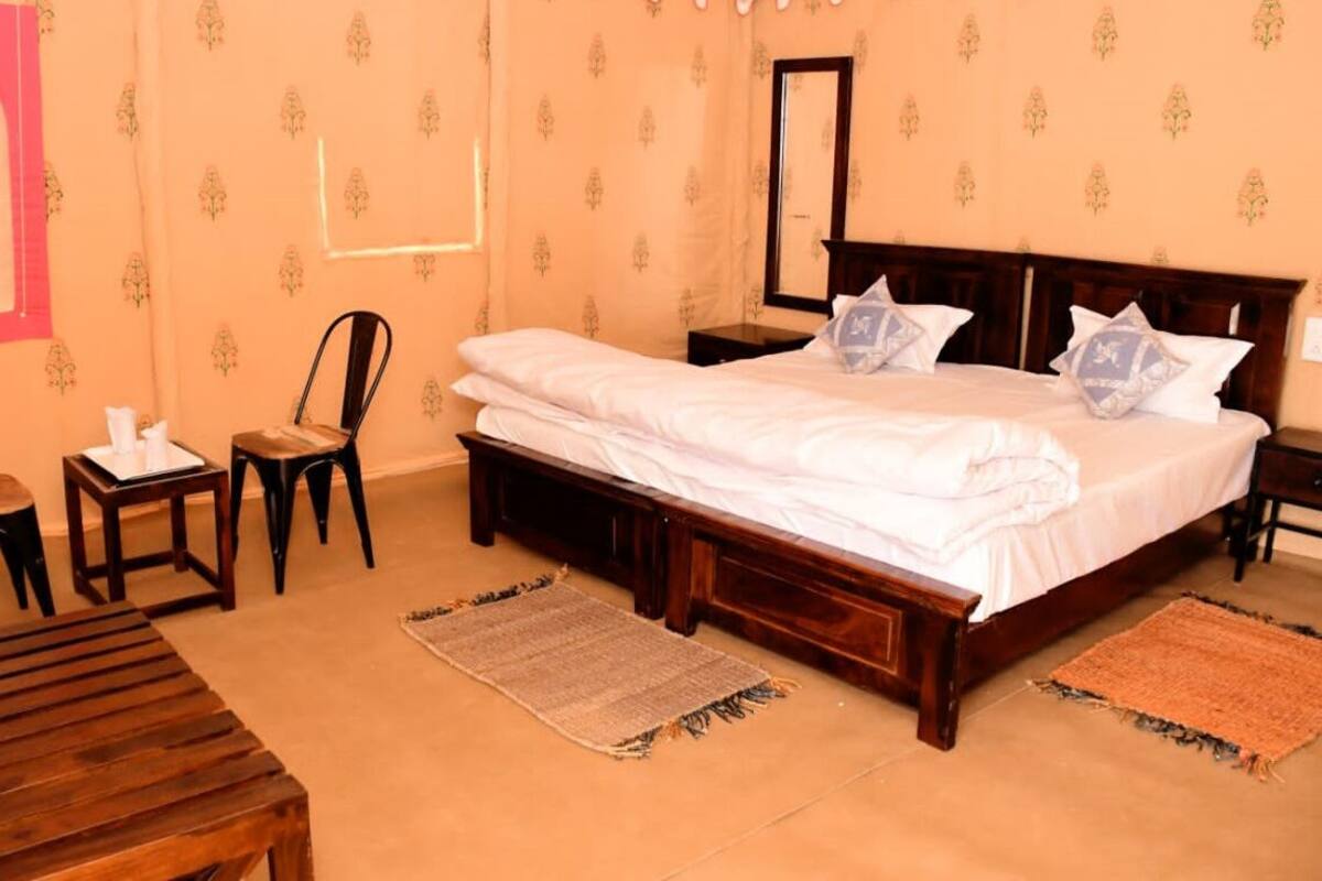 Une chambre à coucher avec un grand lit, deux tables de chevet, une chaise en bois, une petite table et un miroir décoratif.