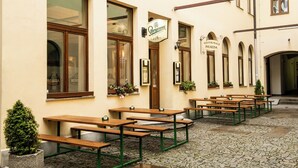 An outdoor seating area with wooden benches and a stone floor. - Beseda Accomodation (Ceské Budejovice)