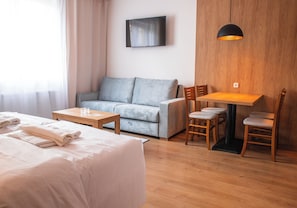 A hotel room with a bed, a sofa, a table, and a TV. - Beseda Accomodation (Ceské Budejovice)