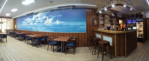 A restaurant with a nautical mural, wooden tables and chairs, and a bar area with shelves of bottles. - Beseda Accomodation (Ceské Budejovice)