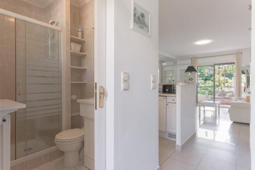 Un baño moderno con cabina de ducha de vidrio, inodoro y lavamanos blanco.
