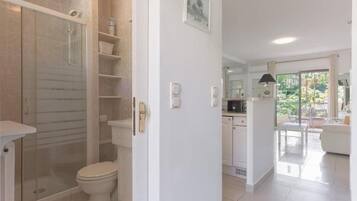 Un baño moderno con cabina de ducha de vidrio, inodoro y lavamanos blanco.