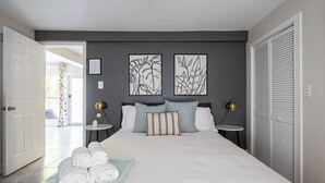 A neatly made bed with white linens, two bedside tables with lamps, and artwork on the wall. - BRIGHT Fort Lauderdale Tropical Retreat (Fort Lauderdale)
