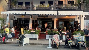 A restaurant with outdoor seating, a covered entrance, and a balcony.