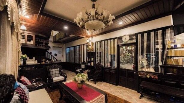 A traditional interior with a chandelier, wooden furniture, and a red carpet.