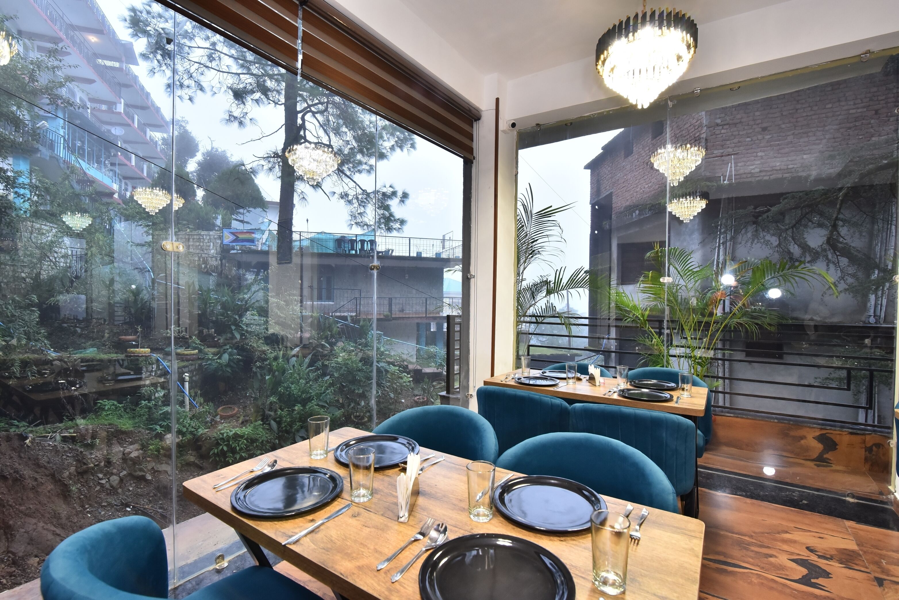 Un ristorante con vista su un giardino e degli edifici. I tavoli sono apparecchiati con piatti, posate e bicchieri.