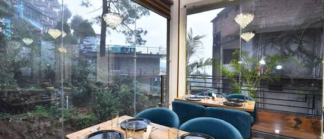 Un ristorante con vista su un giardino e degli edifici. I tavoli sono apparecchiati con piatti, posate e bicchieri.