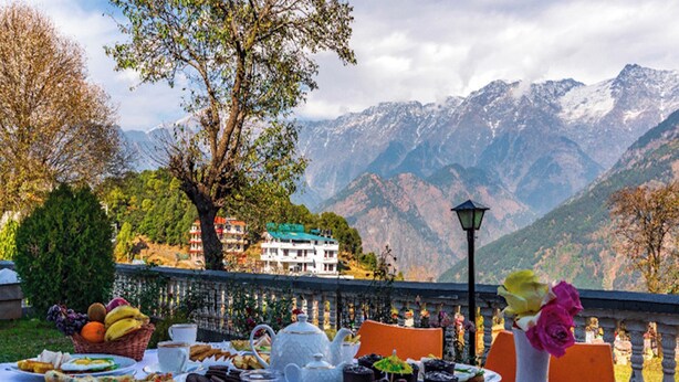 A table set for breakfast with a mountain view in the background. - LA Riqueza Koala Inn Mcleod Ganj - Near to Dalai Lama Temple & Mall Road (Dharamshala)