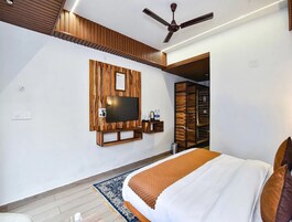 Um quarto moderno com uma cama grande, uma televisão fixada na parede e um ventilador de teto.