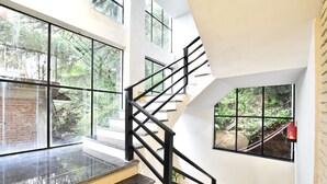 A modern staircase with black railings and glass panels, leading to a lower level. - LA Riqueza Koala Inn Mcleod Ganj - Near to Dalai Lama Temple & Mall Road (Dharamshala)