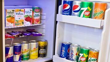A refrigerator stocked with various beverages including Tropicana juice, Pepsi, 7UP, and Mirinda.